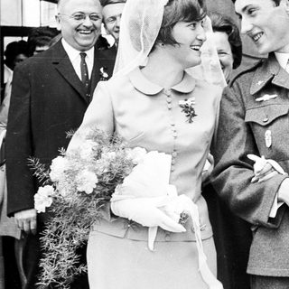 Bride and groom exiting a building, surrounded by guests.