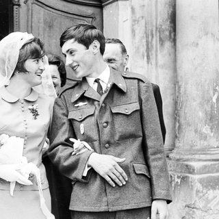 Bride and groom exiting a building, surrounded by guests.
