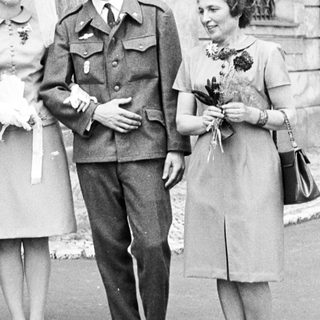 Couple in military uniform pose with family after wedding.