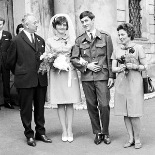 Couple in military uniform pose with family after wedding.