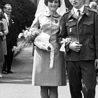 Couple poses after a wedding ceremony with guests present.