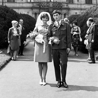 Couple poses after a wedding ceremony with guests present.