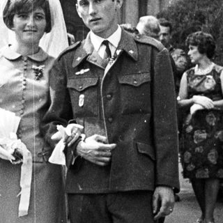 Couple poses after a wedding ceremony with guests present.
