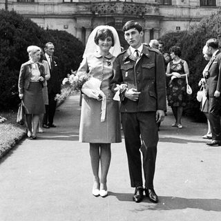Couple poses after a wedding ceremony with guests present.