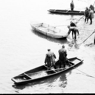 Men near boats, possibly involved in rescue or transport.