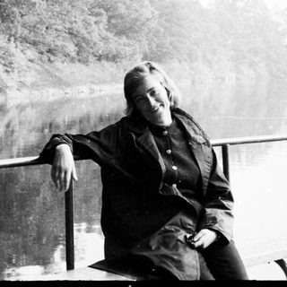 Woman seated on railing overlooking a body of water.