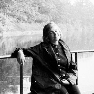 Woman sits on railing overlooking a body of water.