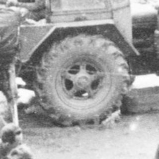 Group of people gather near vehicles and a tent.
