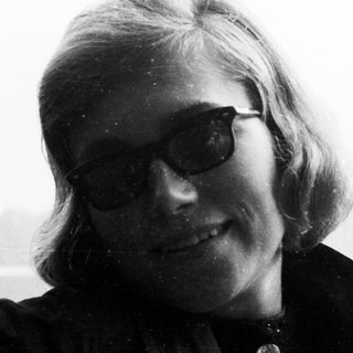 Here's a brief summary of the image: Black and white portrait of a woman wearing sunglasses.