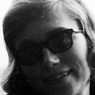 Here's a brief summary of the image: Black and white portrait of a woman wearing sunglasses.