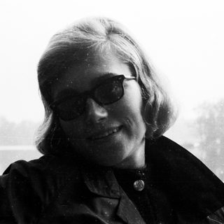 Here's a brief summary of the image: Black and white portrait of a woman wearing sunglasses.