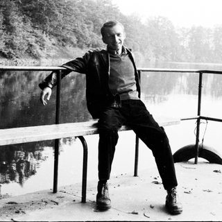 Man sitting on a ledge overlooking a body of water.