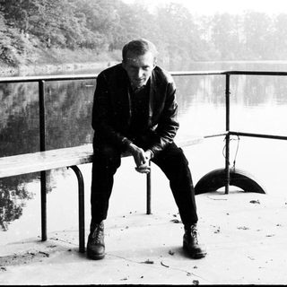 Man sits on a bench overlooking a body of water.