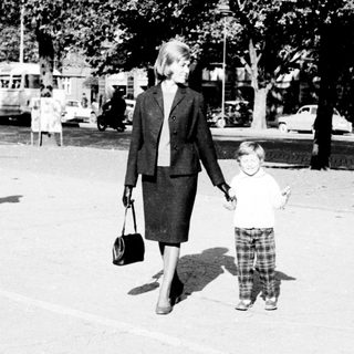 Woman and child walking down a street in a city.