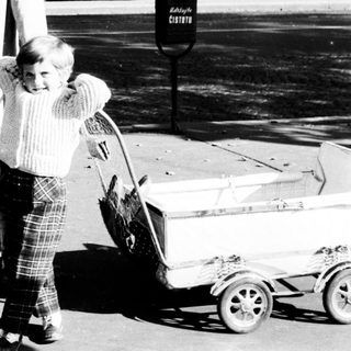 Man and child walk away, pulling a cart.