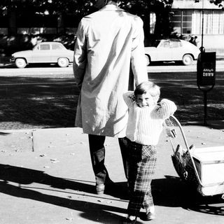 Man and child walk away, pulling a cart.