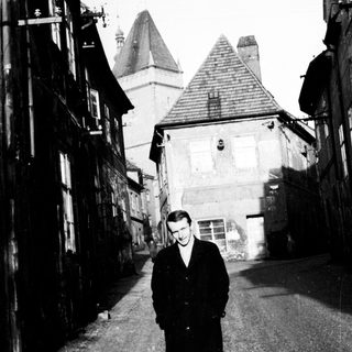 Man stands in a narrow, old European street.