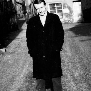 Man stands in a narrow, old European street.