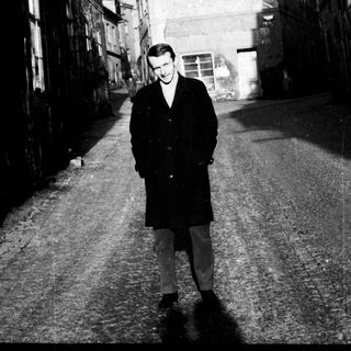 Man stands in a narrow, old European street.