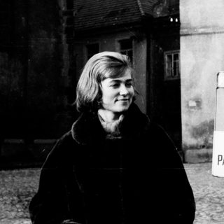 Black and white photo of a woman near a building.