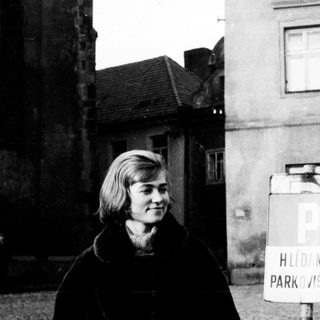Black and white photo of a woman near a building.