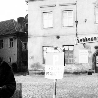 Man stands near a building with a parking sign.