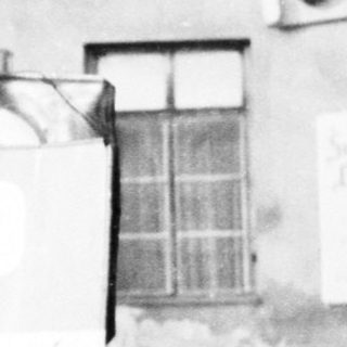 Man stands near a building with a parking sign.