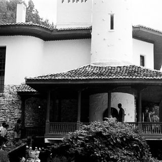 Black and white photo of a large house with people.