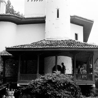 Black and white photo of a large house with people.