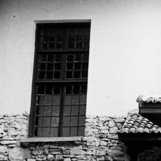 Black and white photo of a large house with people.