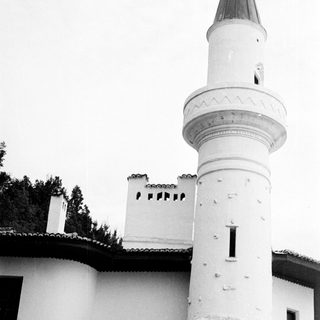 Black and white image of a white minaret and building.