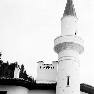 Black and white image of a white minaret and building.