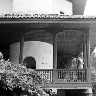 Statue on balcony of building with arched doorway.