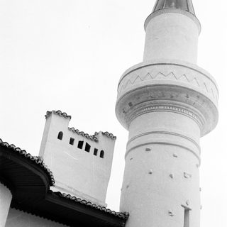 Black and white photo of a mosque minaret and building.