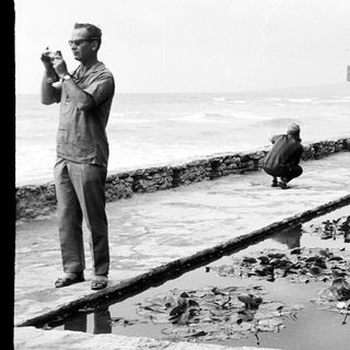 Man taking a photo near a lily pond and ocean.