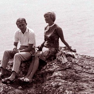 Couple seated on a rocky cliff overlooking the sea.