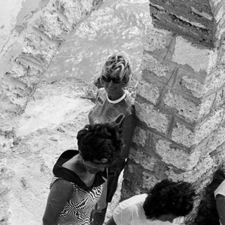 Black and white photo of people near an arched stone structure.