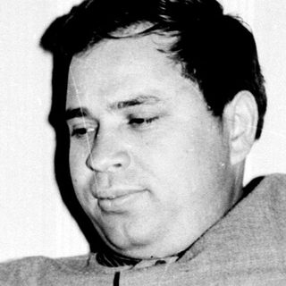 Black and white photo of a man seated in a chair.