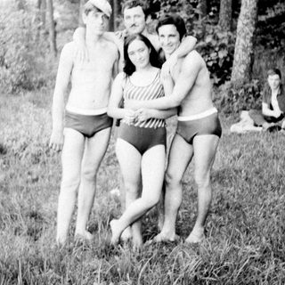 Four people posing near a lake in vintage swimwear.
