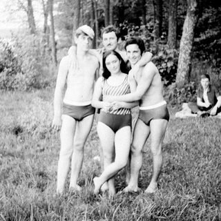 Four people posing near a lake in vintage swimwear.