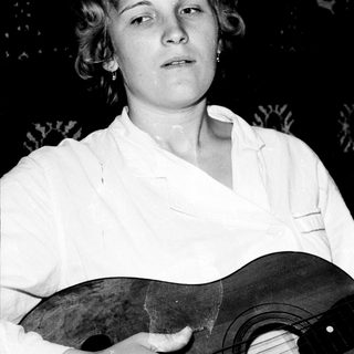 Woman holding an acoustic guitar, black and white portrait.
