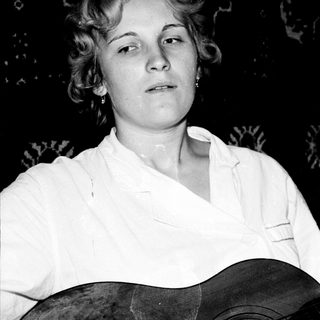 Woman holding an acoustic guitar, black and white portrait.