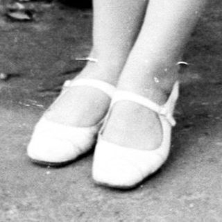 Woman sits on a bench, looking down, handbag nearby.