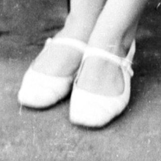 Woman seated on a park bench in a dress.
