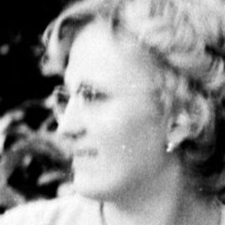 Woman seated on a park bench in a dress.