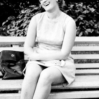 Woman laughs while seated on a park bench.