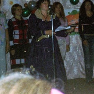 Group singing on stage with microphones.