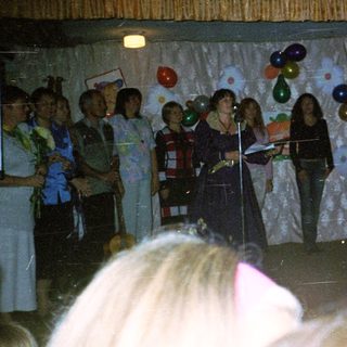 Group singing on stage with microphones.