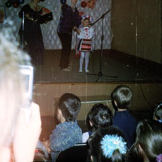Children's stage performance with puppeteers and a young performer.