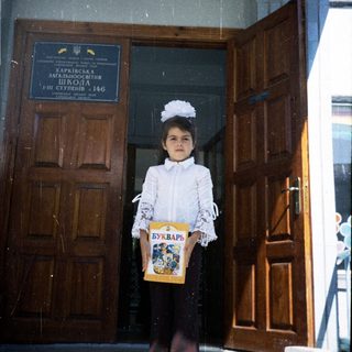 Young girl in first-day school uniform holding a book.